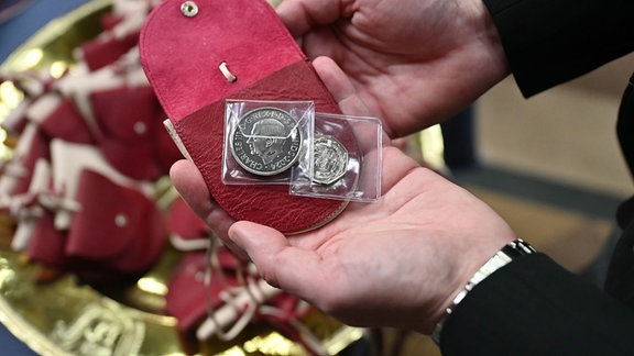 Rote Geldbörsen mit einer 5-Pfund-Münze, auf der ein Tudor-Drache und König Charles III. abgebildet sind, und einer 50-Pence-Münze zum Gedenken an die RNLI, liegen auf einer Schale bevor Königin Camilla diese Münzen bei einer Zeremonie während des königlichen Maundy-Gottesdienstes an Gründonnerstag in der Kathedrale verteilen wird. 