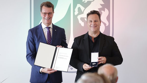 Hendrik Wüst verleiht den Landesverdienstorden an Guido Maria Kretschmer.