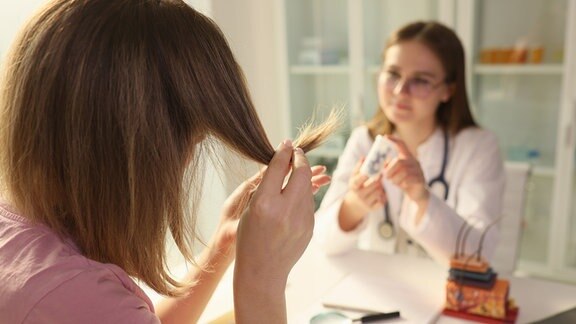 Arzt bietet einer Patientin in der Klinik Medikamente gegen Spliss an.
