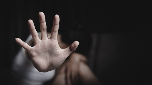 Eine Frau hält ihre Hand schützend vor sich