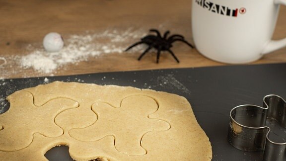 Spinne neben ausgerolltem Teig mit ausgestochenen Figuren