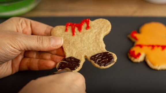 Eine Hand hält eine kopflose Keksfigur.