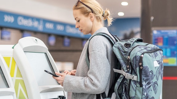 Eine Frau mit Rucksack steht an einem Terminal.
