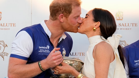 Der britische Prinz Harry (l), und seine Frau Meghan, Herzogin von Sussex, küssen sich