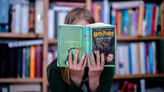 Ein Mädchen liest das Buch Harry Potter und der Orden des Phoenix von Joanne K. Rowling.