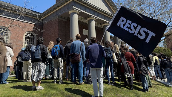 Studenten, Dozenten und Mitglieder der Harvard-Universität versammeln sich zu einem Protest in Cambridge, zu sehen ein Schild mit der Aufschrift "Resist". 