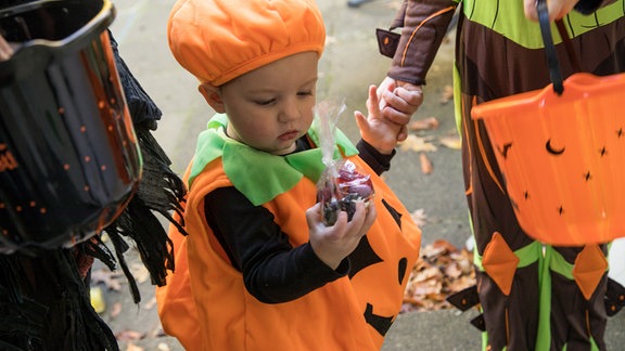 Drei verkleidete Kinder sammeln zu Halloween Suessigkeiten (gestellte Szene).