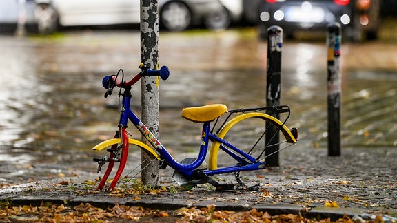 Ein ausgeschlachtetes Kinderfahrrad steht 2020 verlassen an einem Pfahl eines Verkehrsschildes.