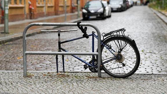 Ein angeschlossenes Fahrrad, dem bereits das Vorderrad, der Sattel, das Licht, die Klingel und die Handgriffe gestohlen wurden, 2019