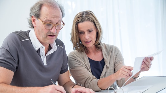 Symbolbild: Ein Mann und eine Frau sitzen am 26.06.2017 an einem Tisch mit Unterlagen und lesen gemeinsam einen Brief (gestellte Szene).