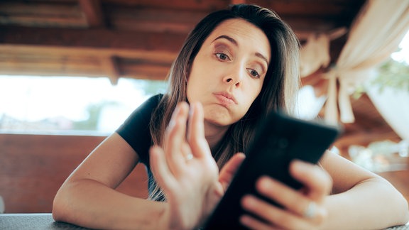 Unglücklche Frau schaut auf Smartphone