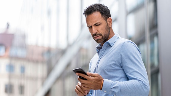 Ein Businessman tippt auf seinem Smartphone, auf der Straße stehend