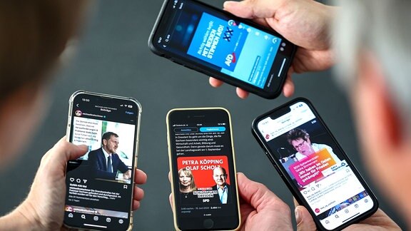 Mehrere Menschen schauen sich Auftritte von Landespolitikern in sozialen Netzwerken auf ihren Mobiltelefonen an