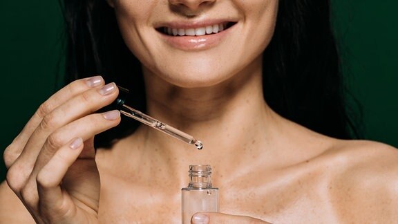 Frau hält Lotion mit Pipette in der Hand