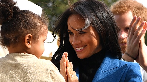 Meghan Markle lächelt ein Kind an