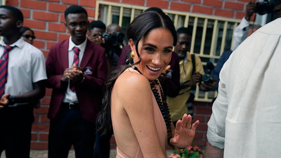 Meghan Markle, Duchess of Sussex, gestikuliert, während sie und Prinz Harry Kinder in der Lights Academy besuchen.