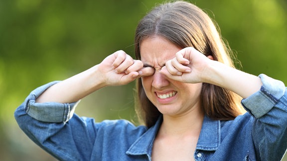 Junge Frau verzieht das Gesicht und reibt sich die Augen.