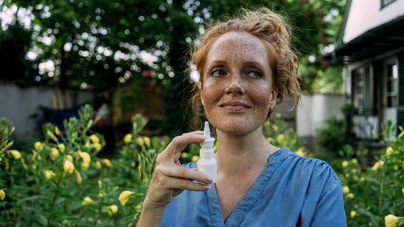 Frau hält Nasenspray.