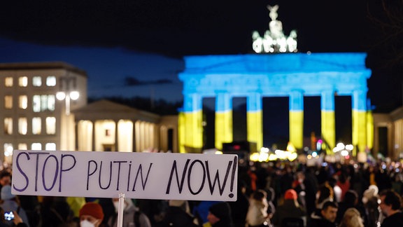 Demonstration vor dem angestrahlten Brandenburger Tor.