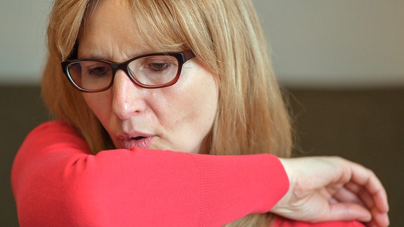 Eine Frau hustet in ihre Armbeuge