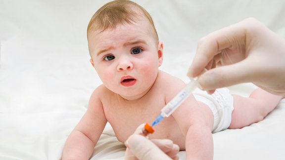 Baby schaut auf Impfspritze