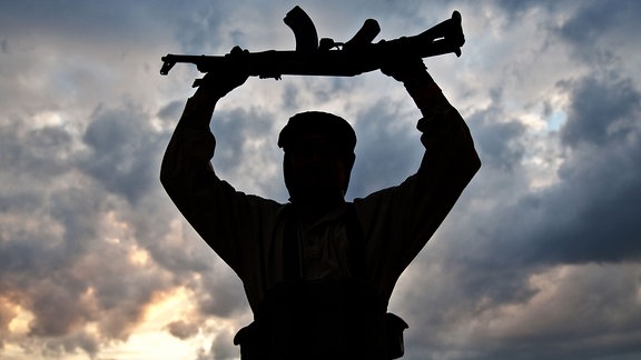 Silhouette eines muslimischen Militanten mit Gewehr.