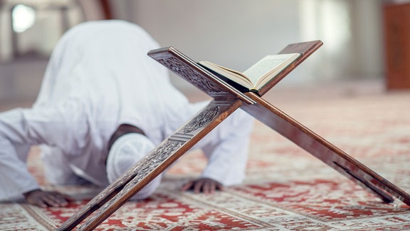 Afrikanischer Muslim, der ein Dishdasha trägt und dabei ein traditionelles Gebet zu Gott spricht.