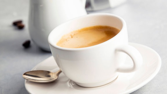Ein Tasse mit Kaffee steht auf einem Tisch.