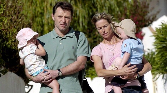 Kate und Gerald McCann gehen mit ihren Zwillingen Sean und Amelie auf dem Arm durchs portugiesische Praia da Luz 