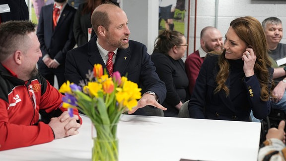 Prinz William und Prinzessin Kate sitzen an einem Tisch mit Rugby-Spielern und unterhalten sich.