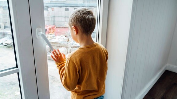 Junge schaut aus dem Fenster.