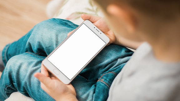 Ein Kind hält ein Smartphone in der Hand.