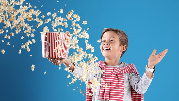 Illustration - Ein Junge lässt Popcorn aus einem Eimer Fliegen.