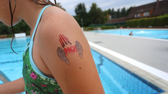 Ein Mädchen mit einem "NO!" Klebetattoo am Arm.