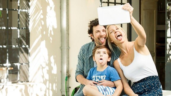 Eine junge Familie mit Kind posiert für ein Selfie
