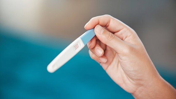 Eine Frau hält einen Schwangerschaftstest in der Hand.