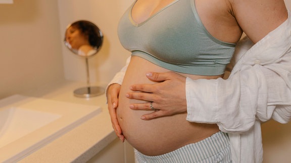 Eine schwangere Frau mit Händen auf dem Bauch