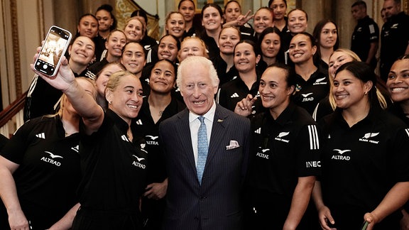 König Charles macht ein Foto mit einem Rugby Team.