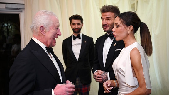 König Charles spricht mit David and Victoria Beckham.