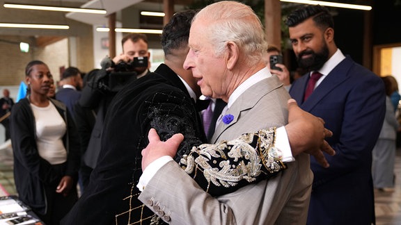 König Charles III: umarmt eine Person.