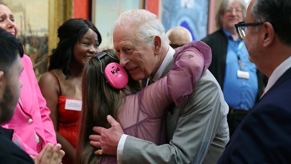 König Charles III. umarmt ein Kind.