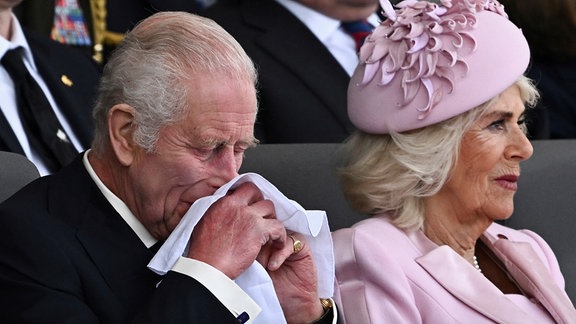 Der britische König Charles III. reagiert neben Königin Camilla