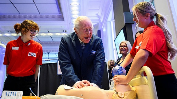 Der britische König Charles III. führt eine Herz-Lungen-Wiederbelebung an einer medizinischen Testpuppe durch, als er an einer Feier für den 1.000sten RCN King's Nursing Cadet im Royal College of Nursing in London teilnimmt.