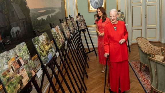 Königin Margerethe geht an Bildern, die auf Staffeleien stehen, vorbei.