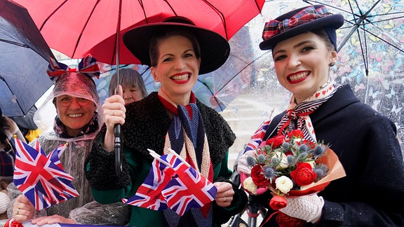Royal-Fans warten bei Regen am Rathausmarkt vor dem Hamburger Rathaus auf die Ankunft des britischen Königs