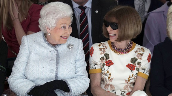 Die britische Königin Elizabeth sitzt neben der Moderedakteurin Anna Wintour.