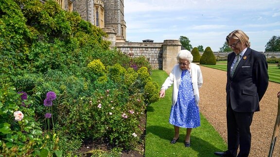 Königin Elisabeth II. betrachtet ein Beet in den Gärten von Schloss Windsor, wo sie eine Duke of Edinburgh-Rose erhielt, die ihr von Keith Weed, Präsident der Royal Horticultural Society, überreicht wurde (rechts).