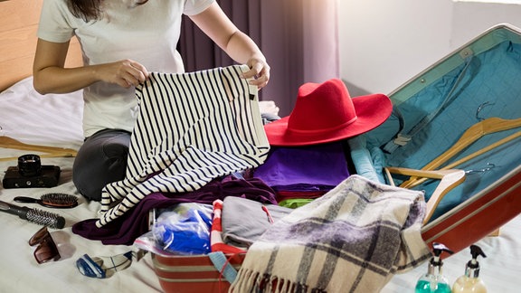 Eine Frau packt einen Koffer.