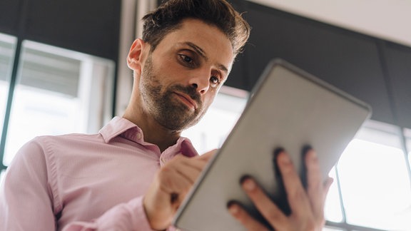 Mann schaut konzentriert auf ein Tablet