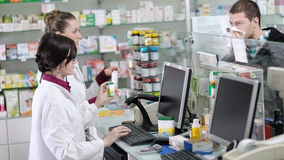 Junge Apothekerinnen empfehlen Kunden Medikamente